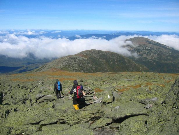 Hikers crossing an alpine ridge above the clouds